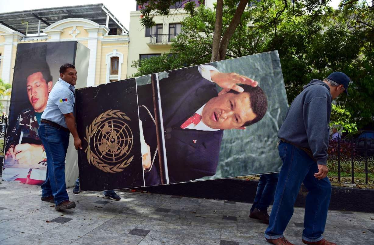 Dos trabajadores retiran del Parlamento una gigantografía del ex presidente Hugo Chávez.